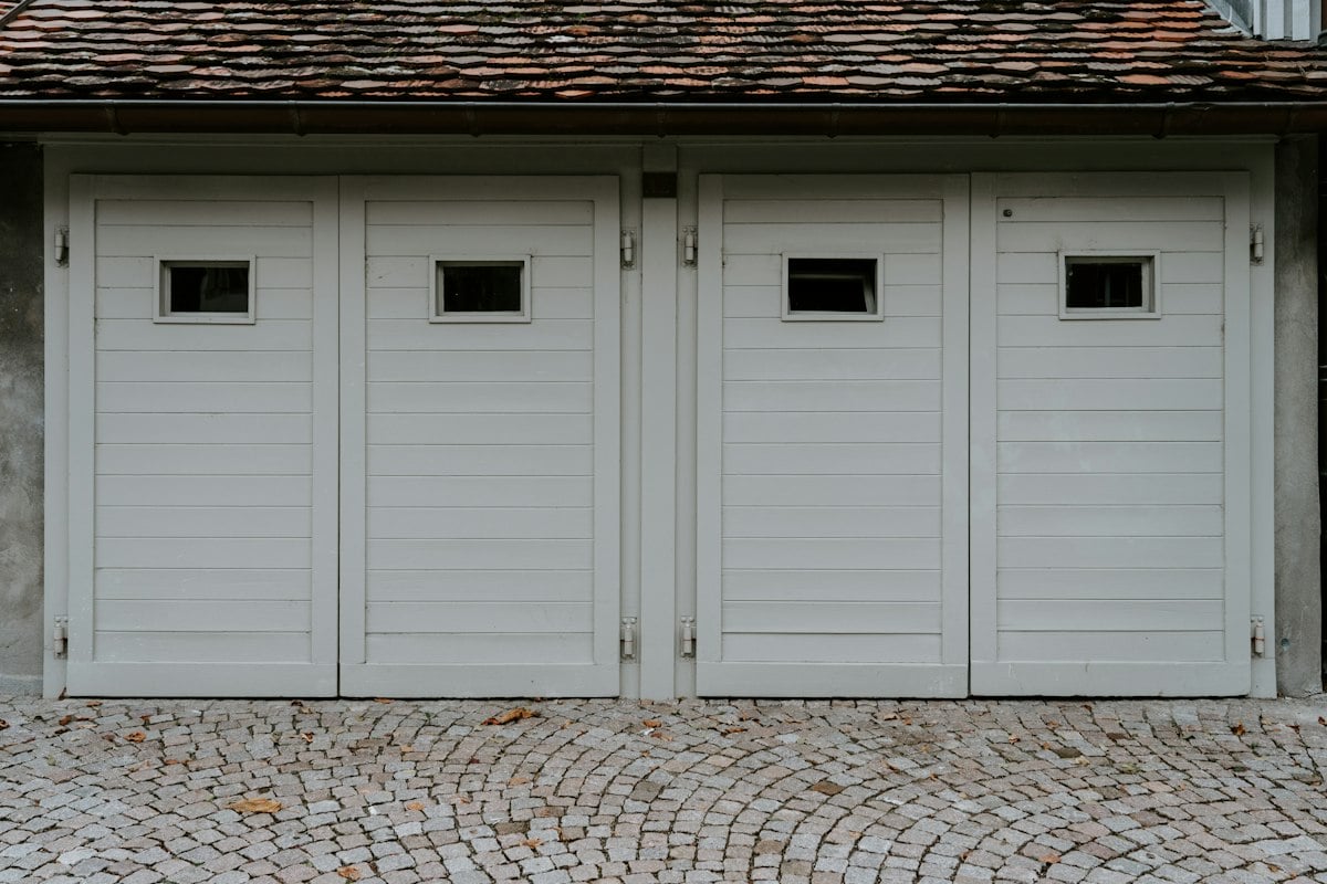 Two white carriage-style garage doors with small windows
